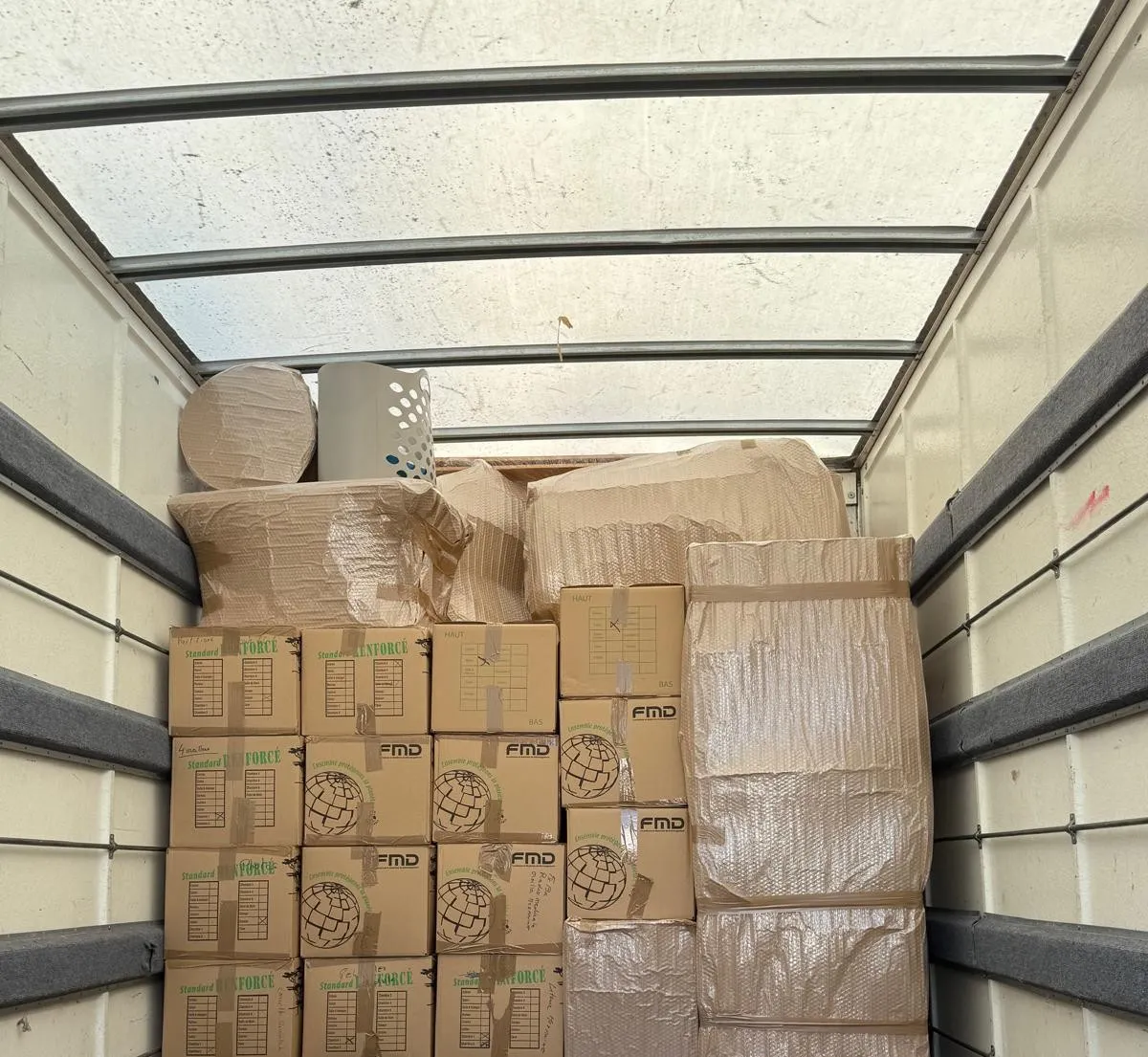 Caisse du camion chargée : cartons empilés et meubles sous papier bulle