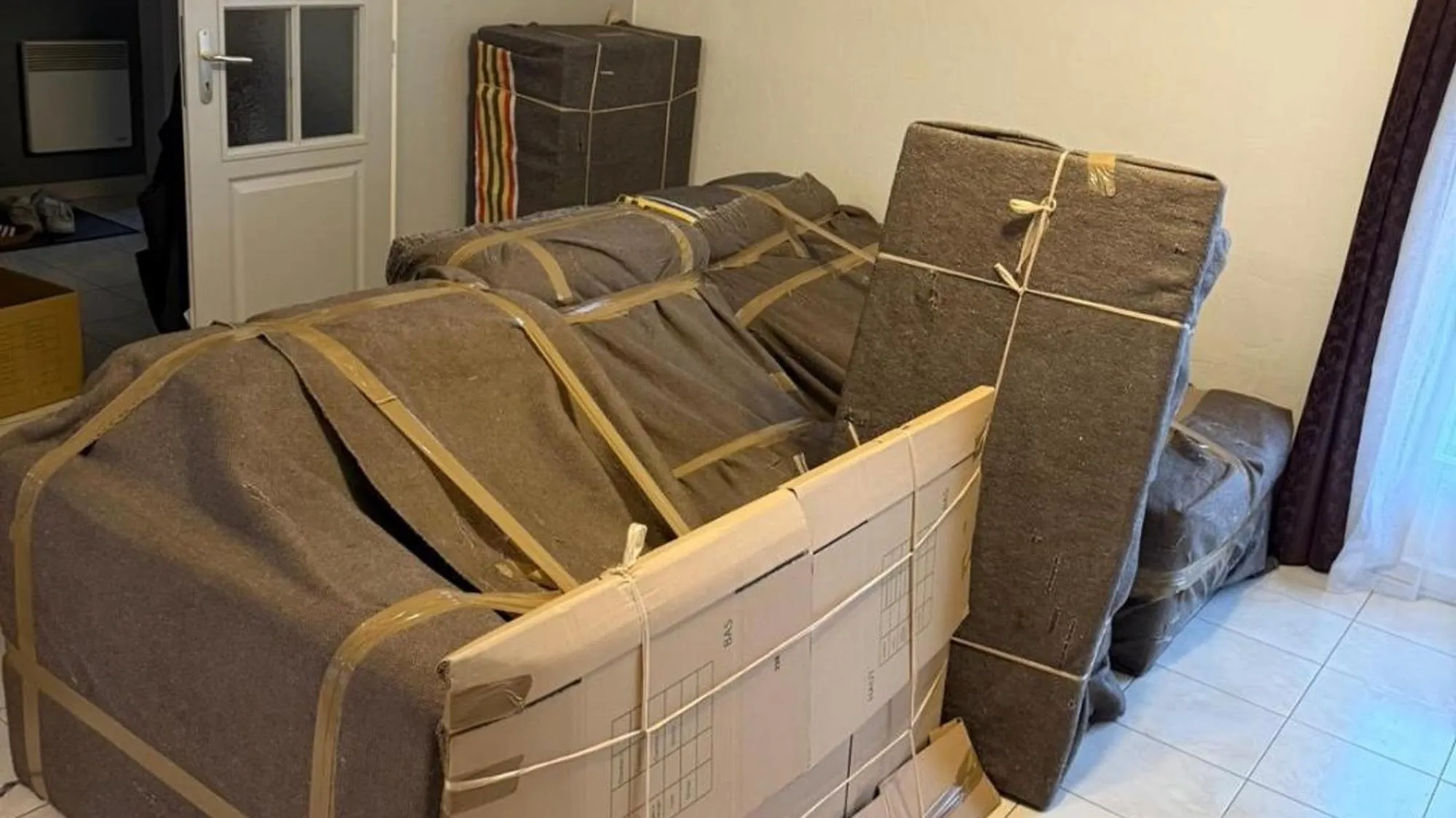 Canapé et fauteuils entièrement emballés sous couverture et sanglés