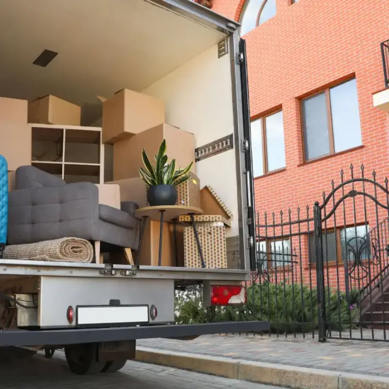 Camion de déménagement chargé avec meubles, cartons et plantes prêt à partir